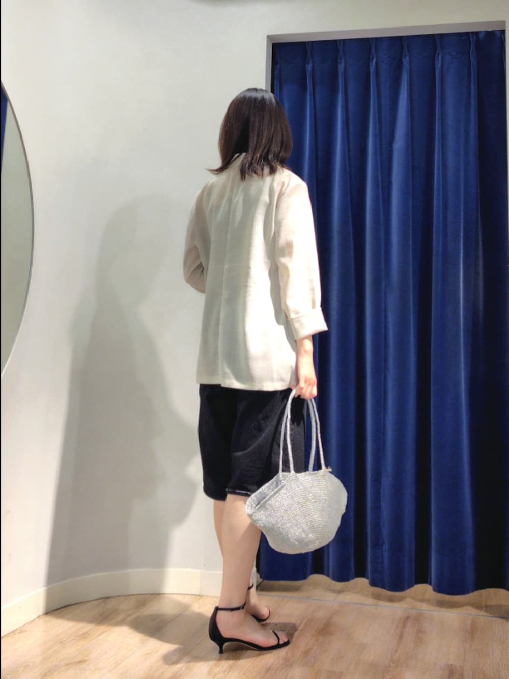 ベージュ系のテーラードジャケット、ホワイト系のタンクトップ、ブラック系のパンツを着用したレディースの夏コーディネートの4枚目の写真