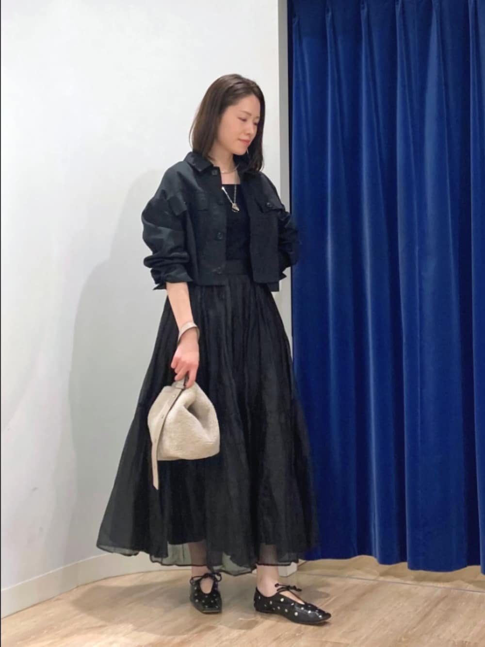 ブラック系のスカート、ブラック系のブルゾン、ベージュ系のショルダーバッグを着用したレディースの秋コーディネートの3枚目の写真
