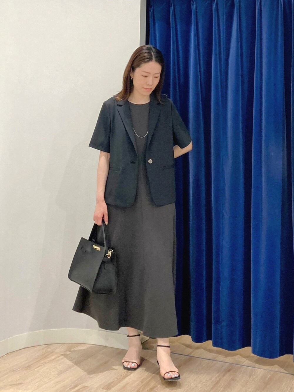 ベージュ系のテーラードジャケット、ブラック系のショルダーバッグ、グレー系のワンピースを着用したレディースの夏コーディネートの2枚目の写真