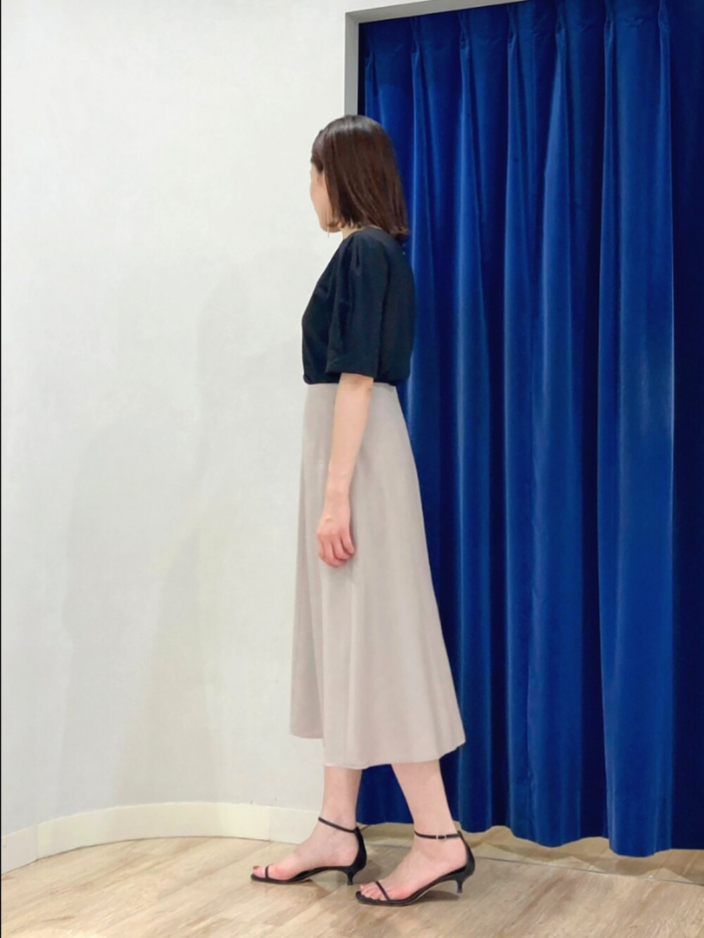 ベージュ系のスカート、ブラック系のTシャツ/カットソー、ゴールド系のピアス（両耳用）を着用したレディースの夏コーディネートの4枚目の写真