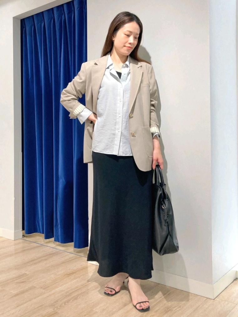 グリーン系のシャツ/ブラウス、ベージュ系のテーラードジャケット、ブラック系のスカートを着用したレディースの秋コーディネートの2枚目の写真