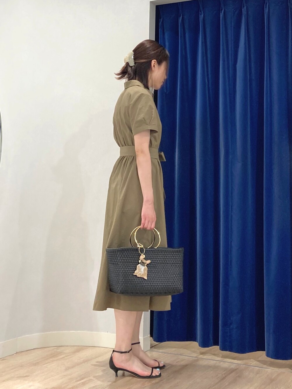 グリーン系のシャツワンピース、ブラック系のかごバッグ、ゴールド系のピアス（両耳用）を着用したレディースの夏コーディネートの5枚目の写真