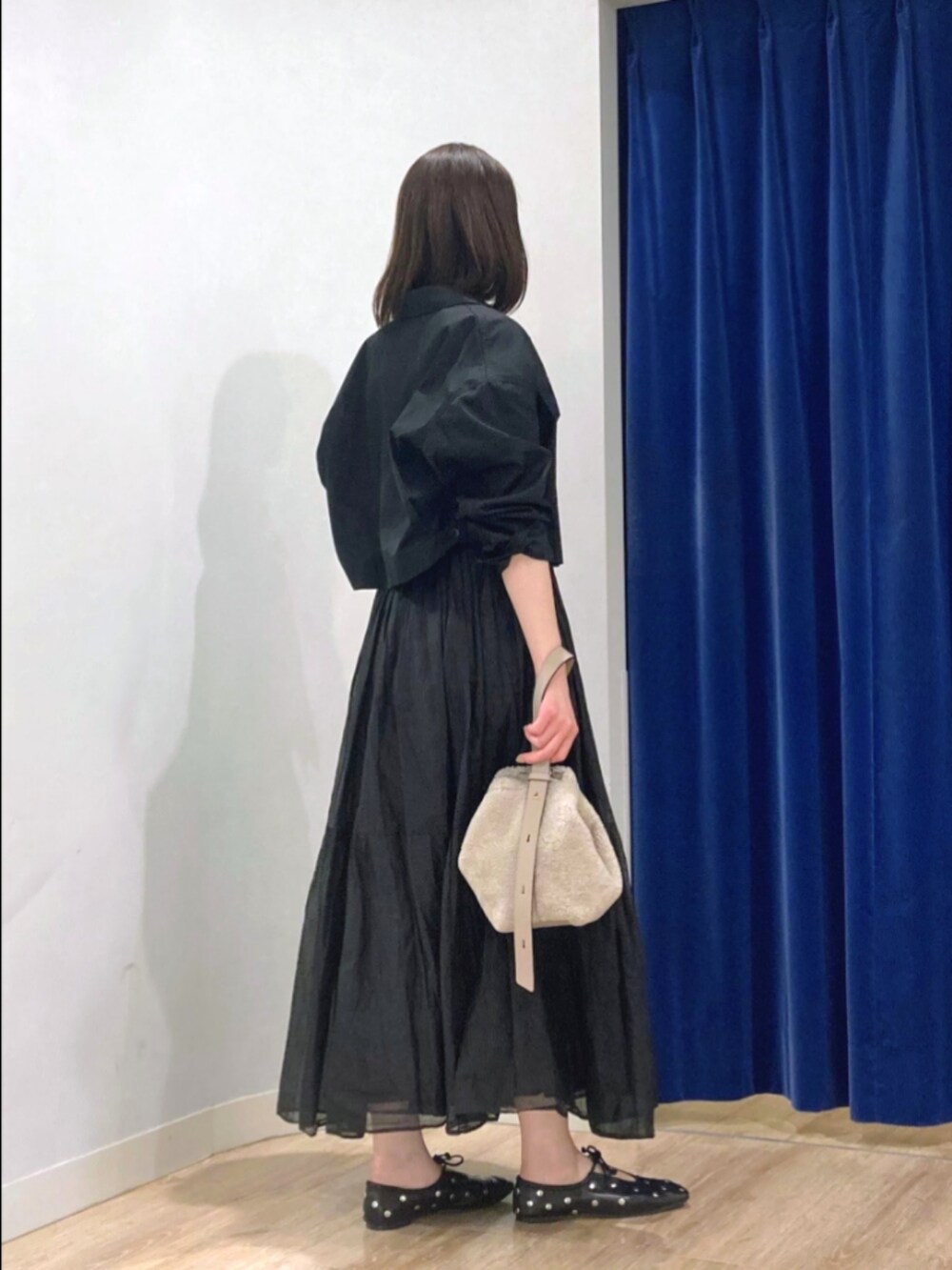 ブラック系のスカート、ブラック系のブルゾン、ベージュ系のショルダーバッグを着用したレディースの秋コーディネートの5枚目の写真