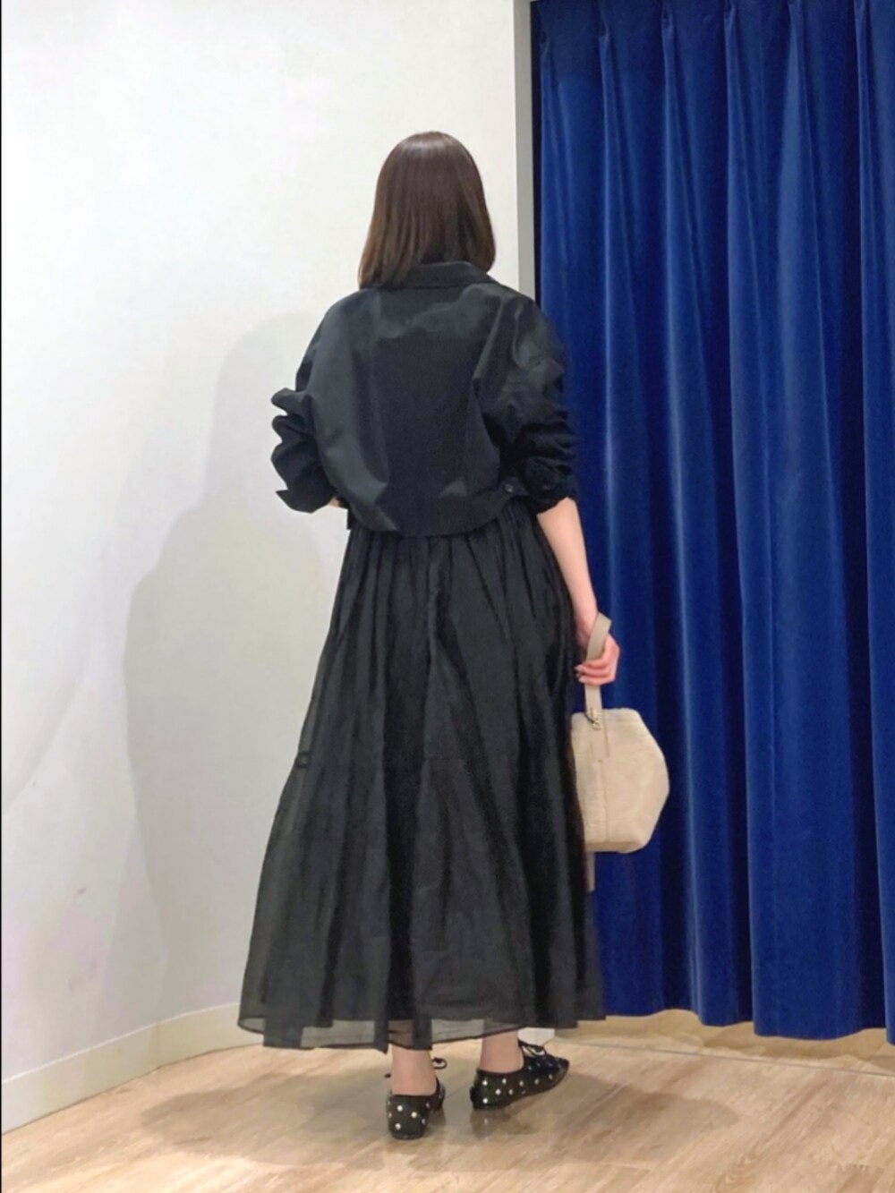 ブラック系のスカート、ブラック系のブルゾン、ベージュ系のショルダーバッグを着用したレディースの秋コーディネートの6枚目の写真