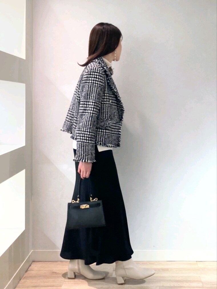 ブラック系のショルダーバッグ、ホワイト系のブーツ、ブラック系のスカートを着用したレディースの冬コーディネートの4枚目の写真