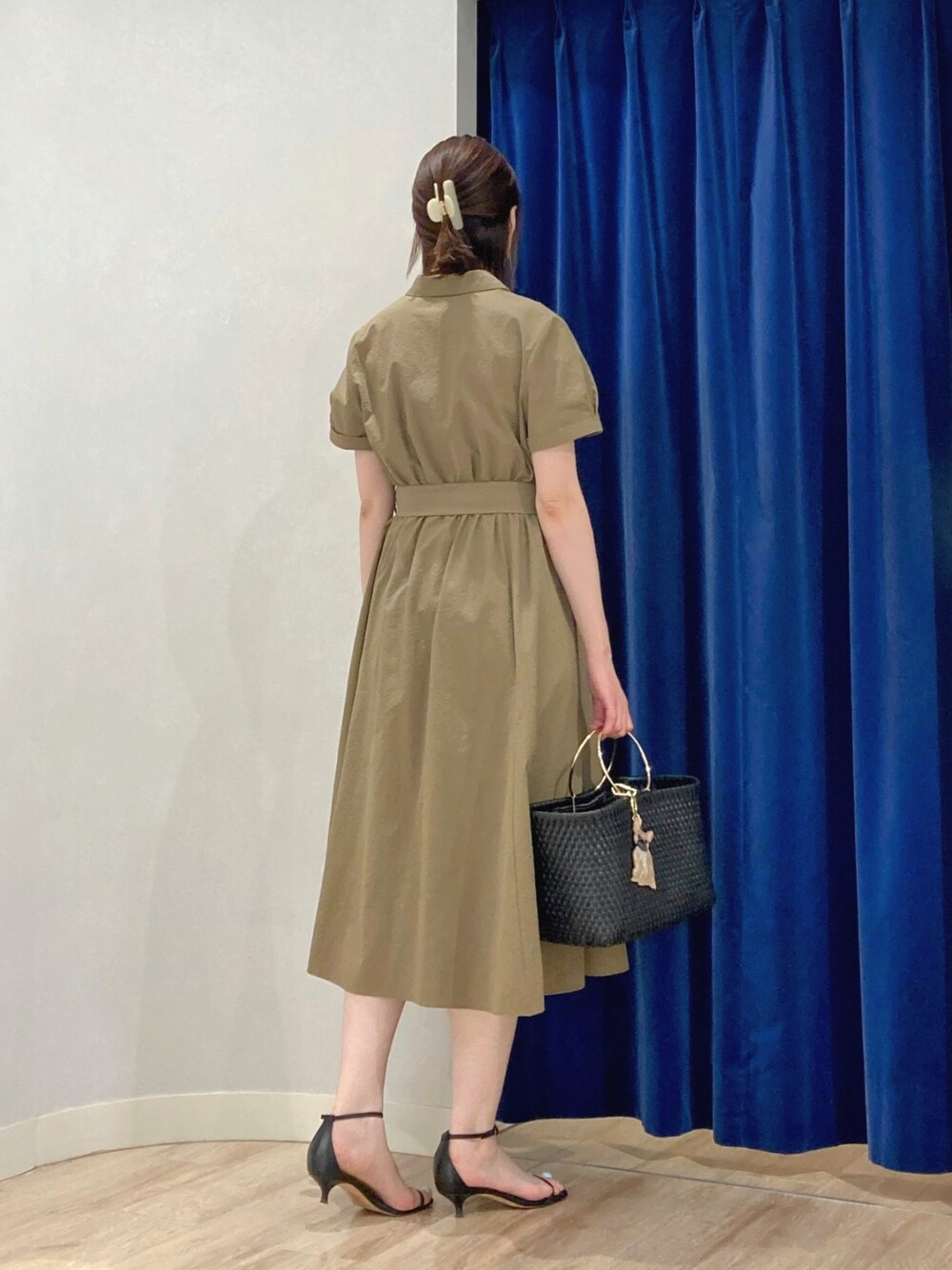 グリーン系のシャツワンピース、ブラック系のかごバッグ、ゴールド系のピアス（両耳用）を着用したレディースの夏コーディネートの6枚目の写真