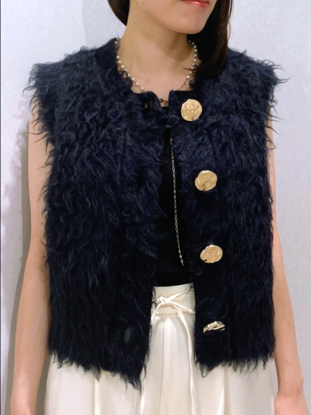 ブルー系のベスト、ブラック系のタンクトップ、ブラウン系のその他パンツを着用したレディースの秋コーディネートの7枚目の写真