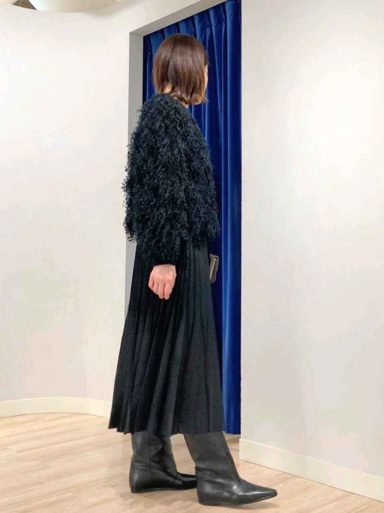 ブラック系のニット/セーター、グレー系のバッグ、ホワイト系のダウンジャケット/コートを着用したレディースの秋コーディネートの3枚目の写真