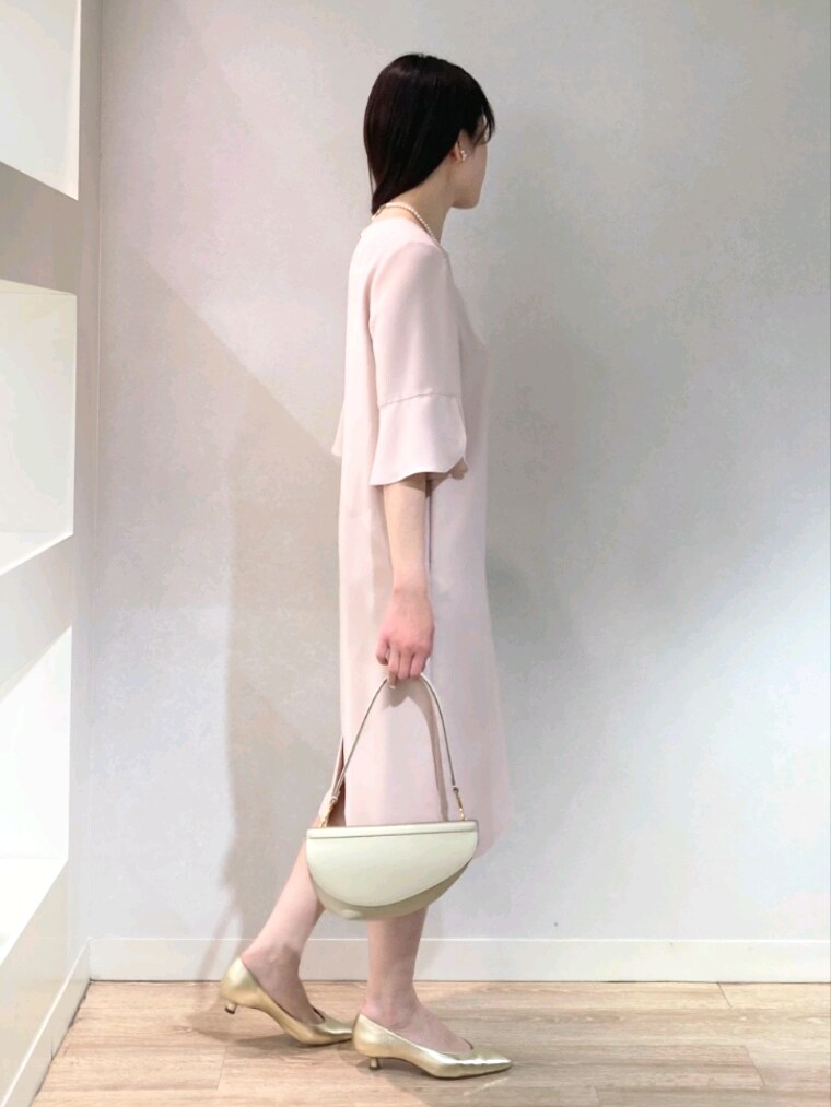 ピンク系のワンピース、ゴールド系のパンプス、ホワイト系のショルダーバッグを着用したレディースの春コーディネートの3枚目の写真