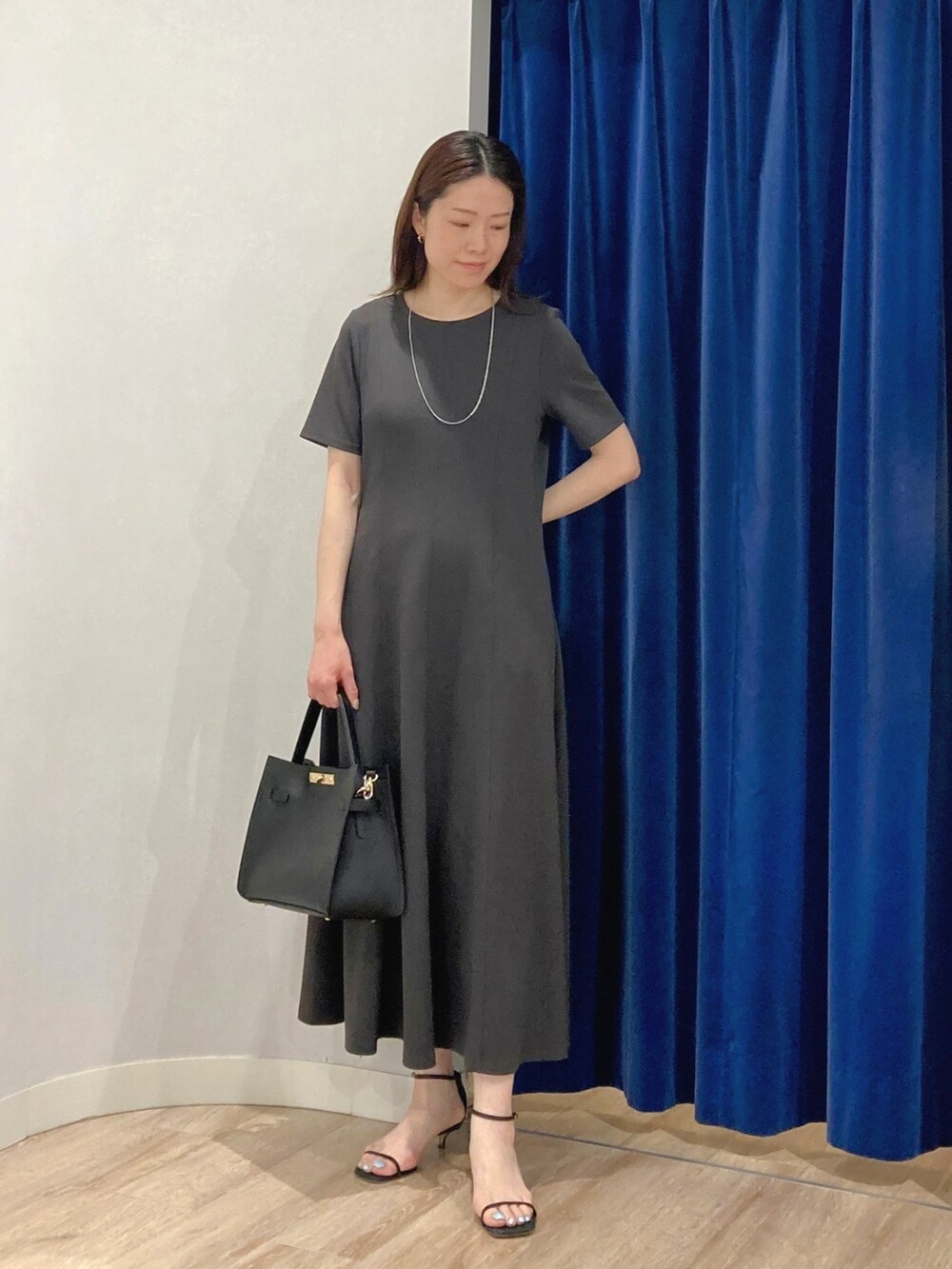 ベージュ系のテーラードジャケット、ブラック系のショルダーバッグ、グレー系のワンピースを着用したレディースの夏コーディネートの6枚目の写真