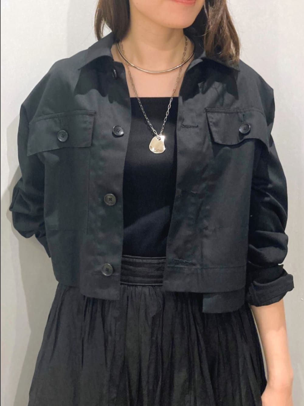 ブラック系のスカート、ブラック系のブルゾン、ベージュ系のショルダーバッグを着用したレディースの秋コーディネートの7枚目の写真