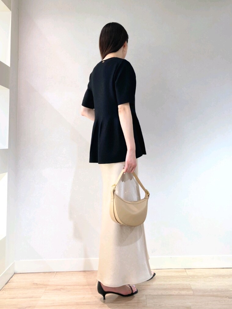 ブラック系のニット/セーター、ベージュ系のショルダーバッグ、ベージュ系のスカートを着用したレディースの春コーディネートの5枚目の写真