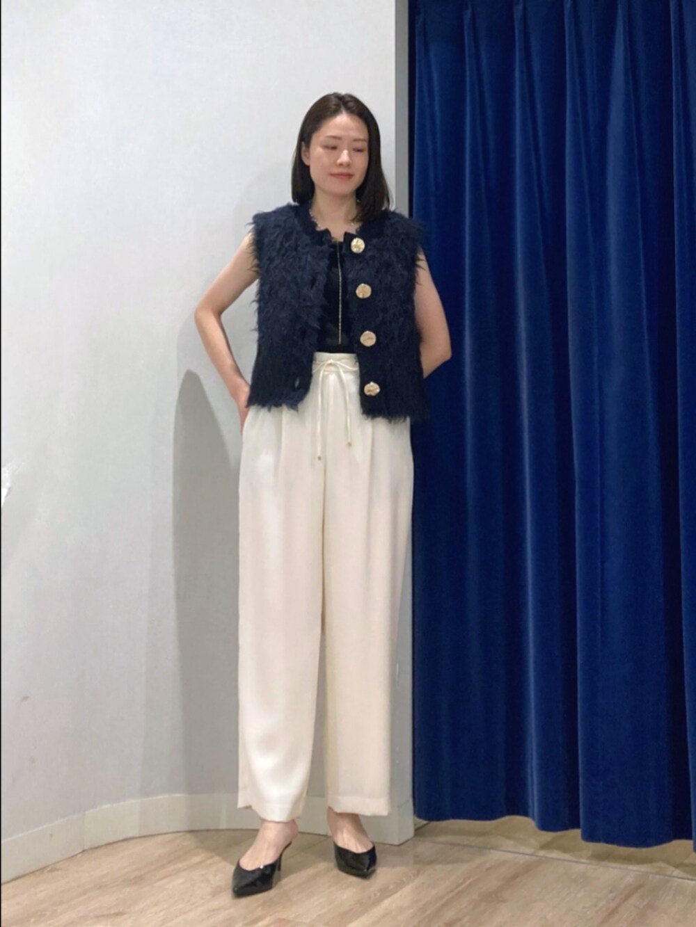 ブルー系のベスト、ブラック系のタンクトップ、ブラウン系のその他パンツを着用したレディースの秋コーディネートの2枚目の写真