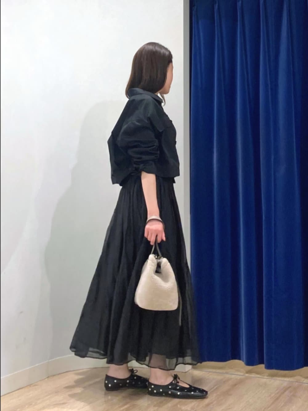 ブラック系のスカート、ブラック系のブルゾン、ベージュ系のショルダーバッグを着用したレディースの秋コーディネートの4枚目の写真