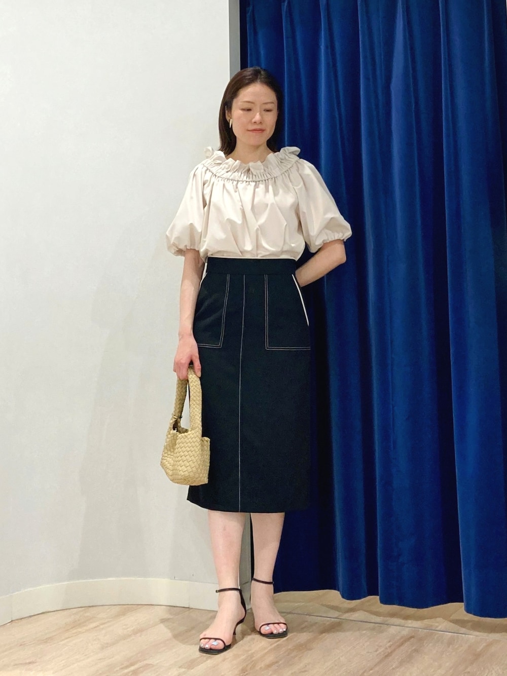 ブラック系のスカート、ベージュ系のシャツ/ブラウス、ベージュ系のショルダーバッグを着用したレディースの夏コーディネートの2枚目の写真
