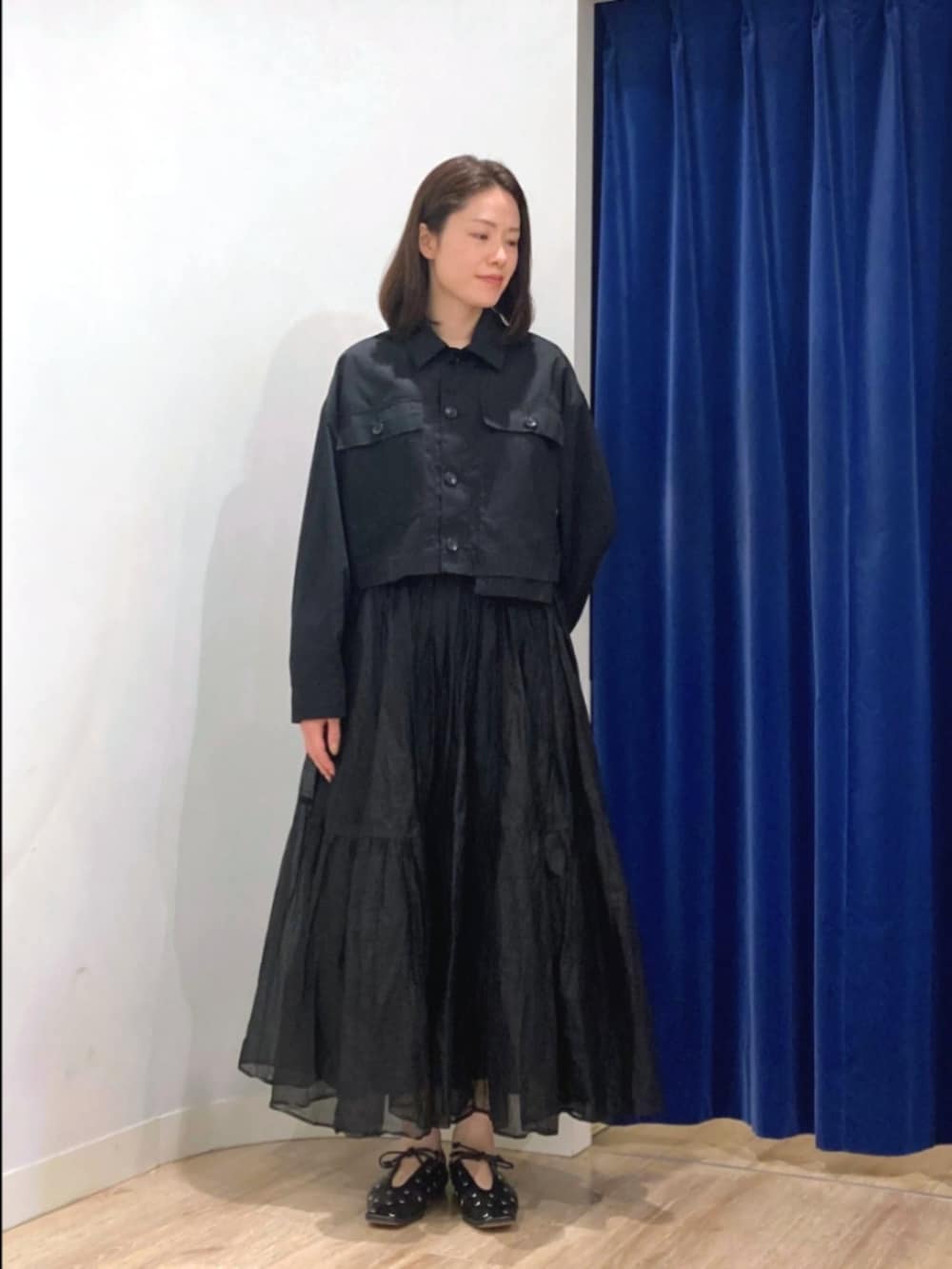 ブラック系のスカート、ブラック系のブルゾン、ベージュ系のショルダーバッグを着用したレディースの秋コーディネートの9枚目の写真