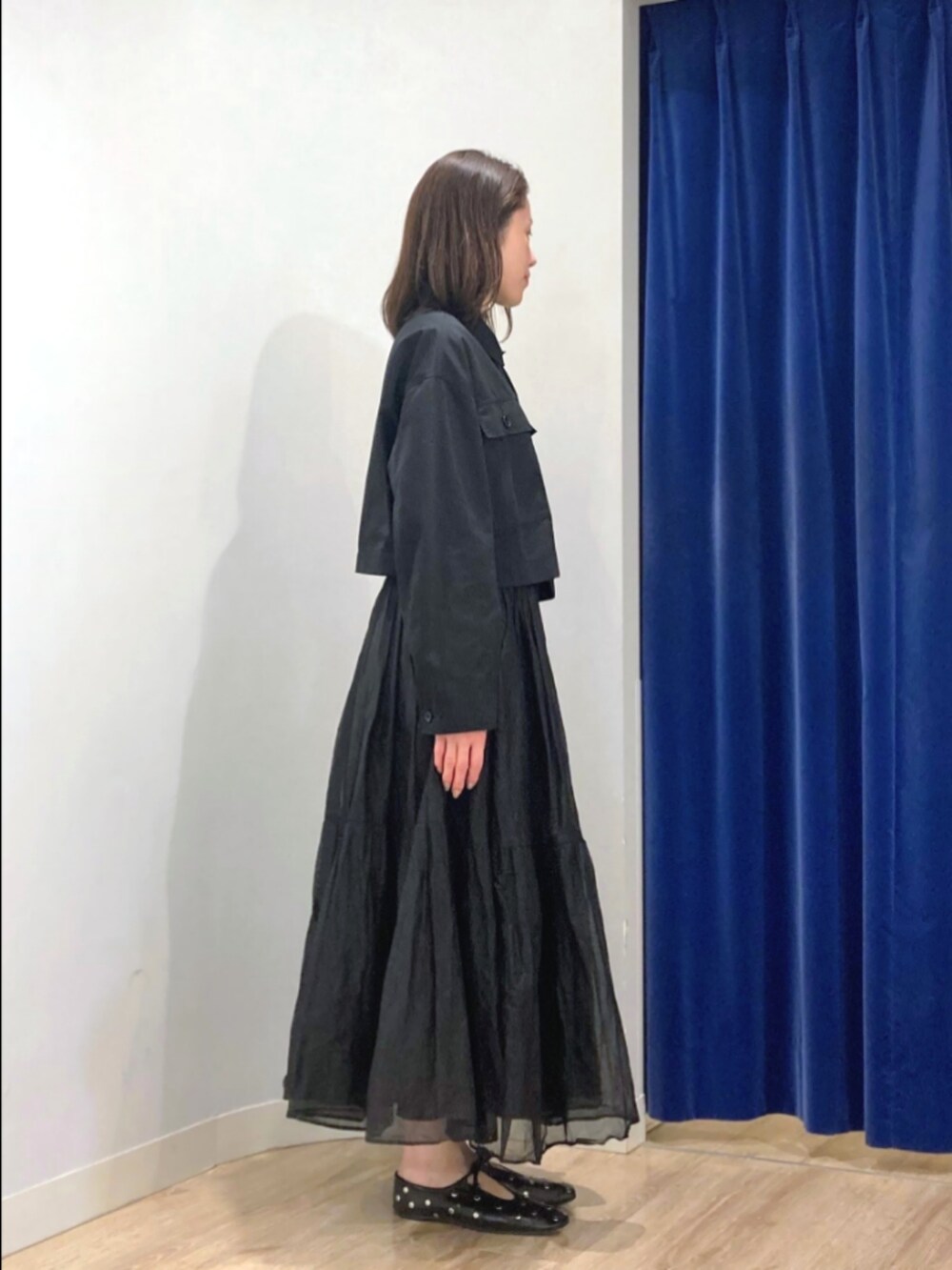 ブラック系のスカート、ブラック系のブルゾン、ベージュ系のショルダーバッグを着用したレディースの秋コーディネートの10枚目の写真