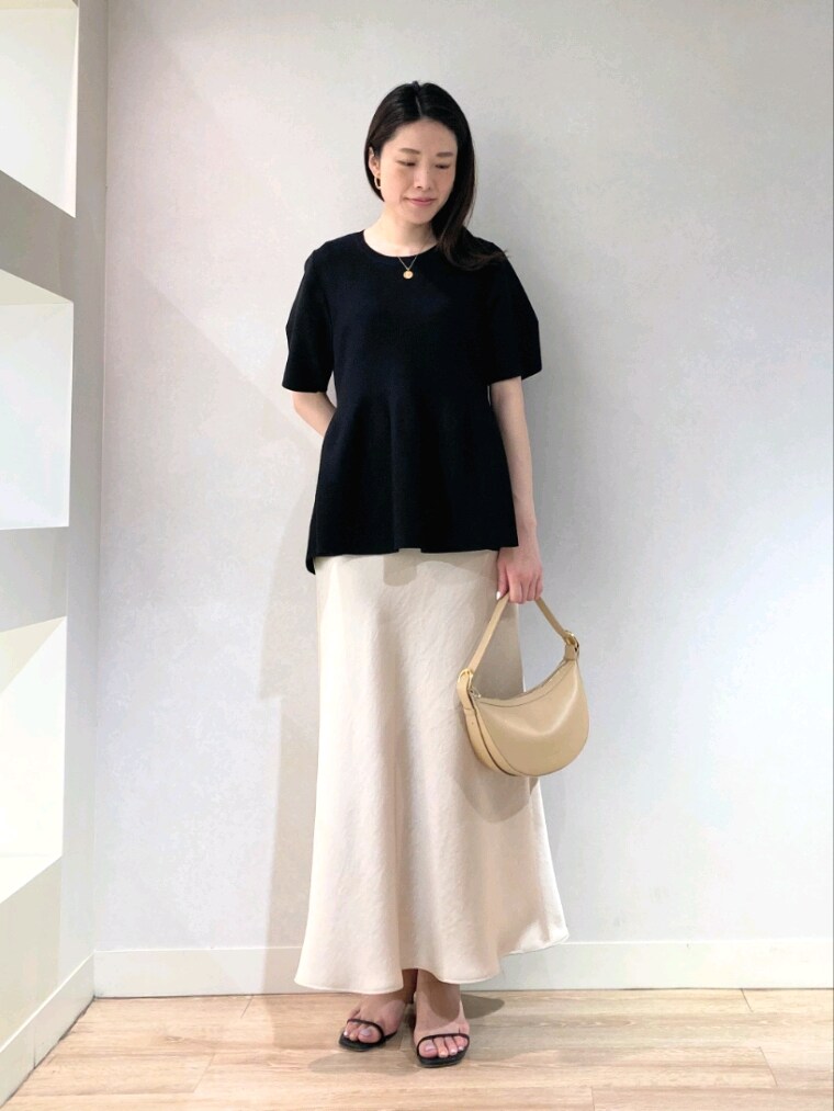 ブラック系のニット/セーター、ベージュ系のショルダーバッグ、ベージュ系のスカートを着用したレディースの春コーディネートの2枚目の写真