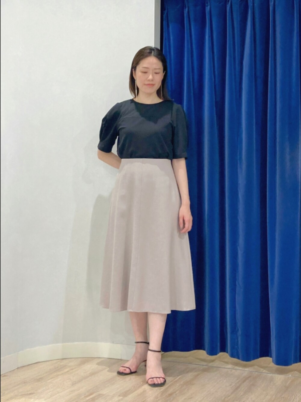 ベージュ系のスカート、ブラック系のTシャツ/カットソー、ゴールド系のピアス（両耳用）を着用したレディースの夏コーディネートの2枚目の写真