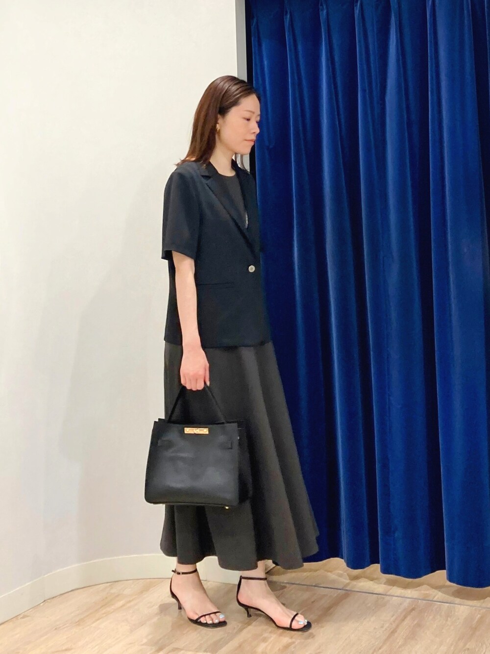 ベージュ系のテーラードジャケット、ブラック系のショルダーバッグ、グレー系のワンピースを着用したレディースの夏コーディネートの3枚目の写真
