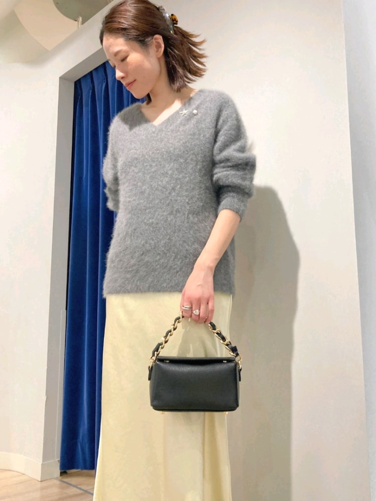 グレー系のニット/セーター、ブラック系のショルダーバッグ、イエロー系のスカートを着用したレディースの秋コーディネートの6枚目の写真