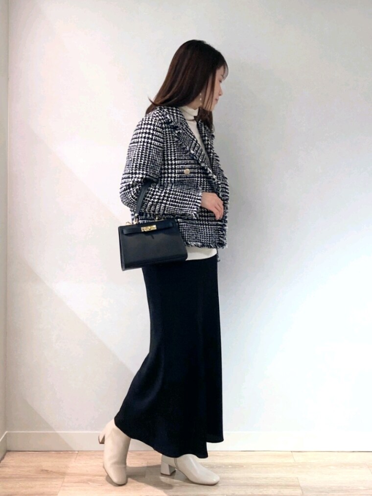 ブラック系のショルダーバッグ、ホワイト系のブーツ、ブラック系のスカートを着用したレディースの冬コーディネートの3枚目の写真