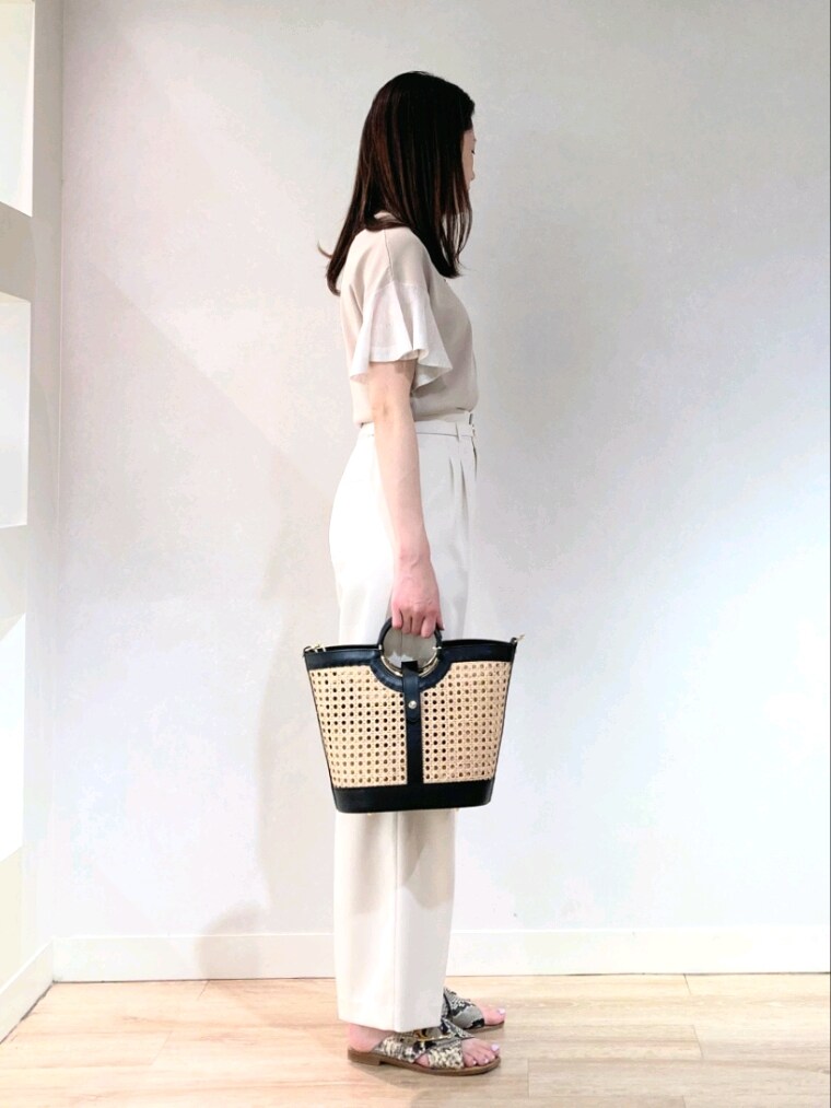 ベージュ系のニット/セーター、ブラック系のトートバッグ、ゴールド系のネックレスを着用したレディースの夏コーディネートの3枚目の写真