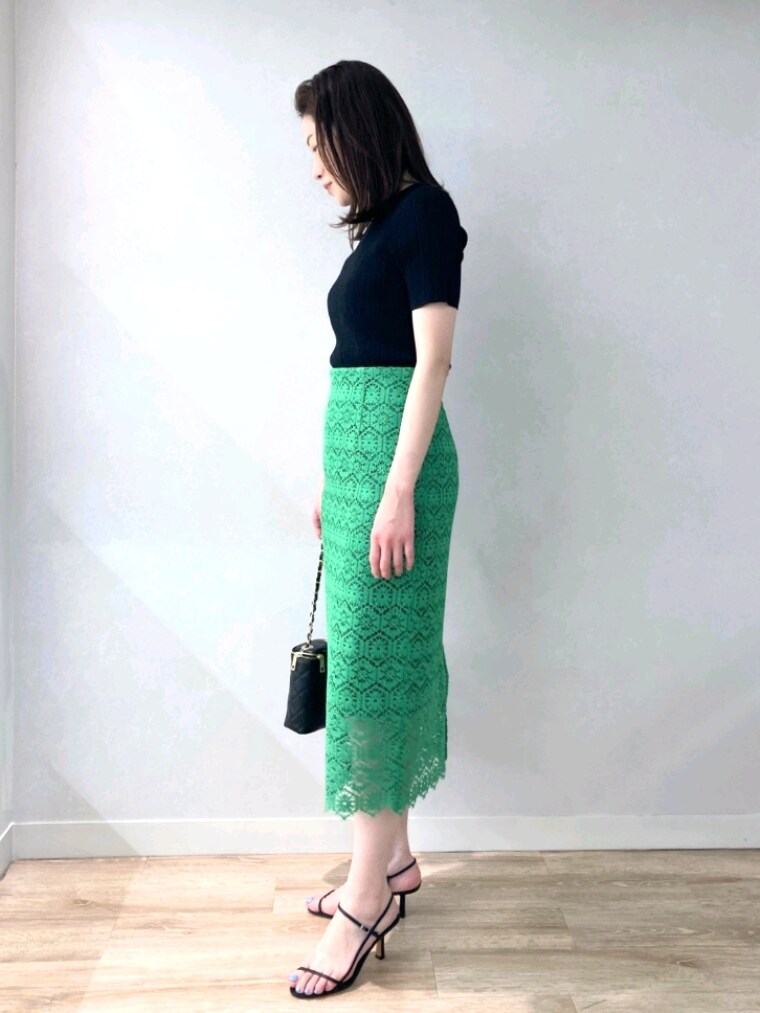 ブラック系のニット/セーター、グリーン系のスカート、ブラック系のサンダルを着用したレディースの春コーディネートの6枚目の写真