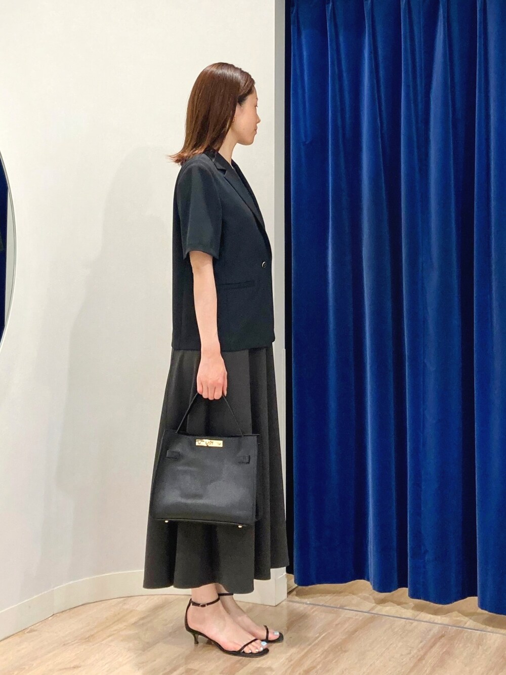 ベージュ系のテーラードジャケット、ブラック系のショルダーバッグ、グレー系のワンピースを着用したレディースの夏コーディネートの4枚目の写真