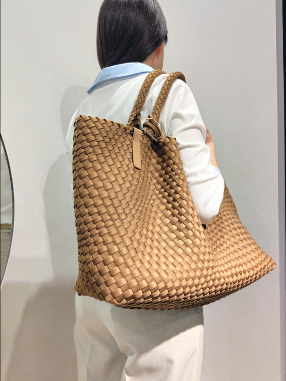 ブラウン系のトートバッグ、ベージュ系のその他パンツ、ホワイト系のニット/セーターを着用したレディースの春コーディネートの7枚目の写真