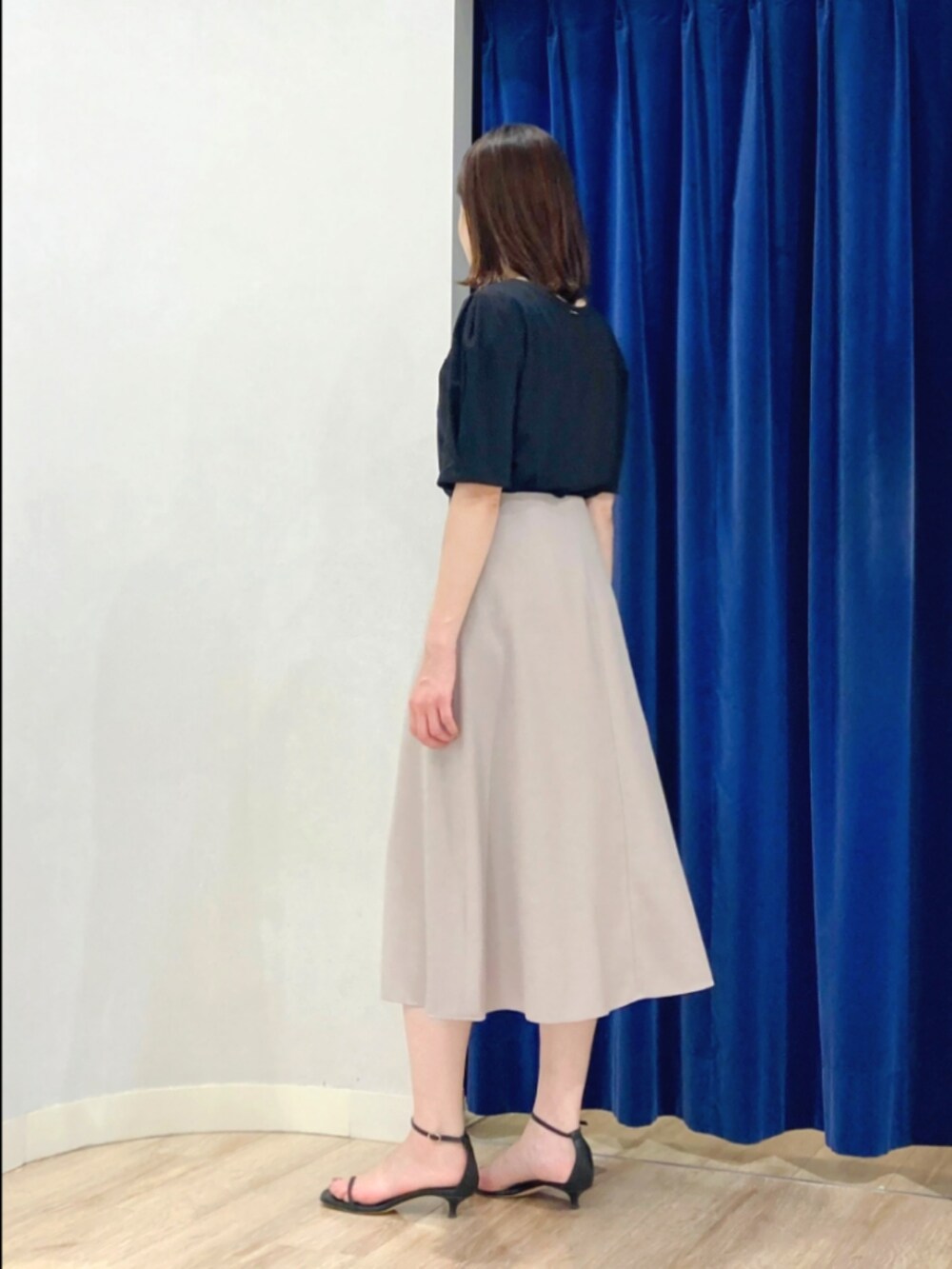 ベージュ系のスカート、ブラック系のTシャツ/カットソー、ゴールド系のピアス（両耳用）を着用したレディースの夏コーディネートの6枚目の写真