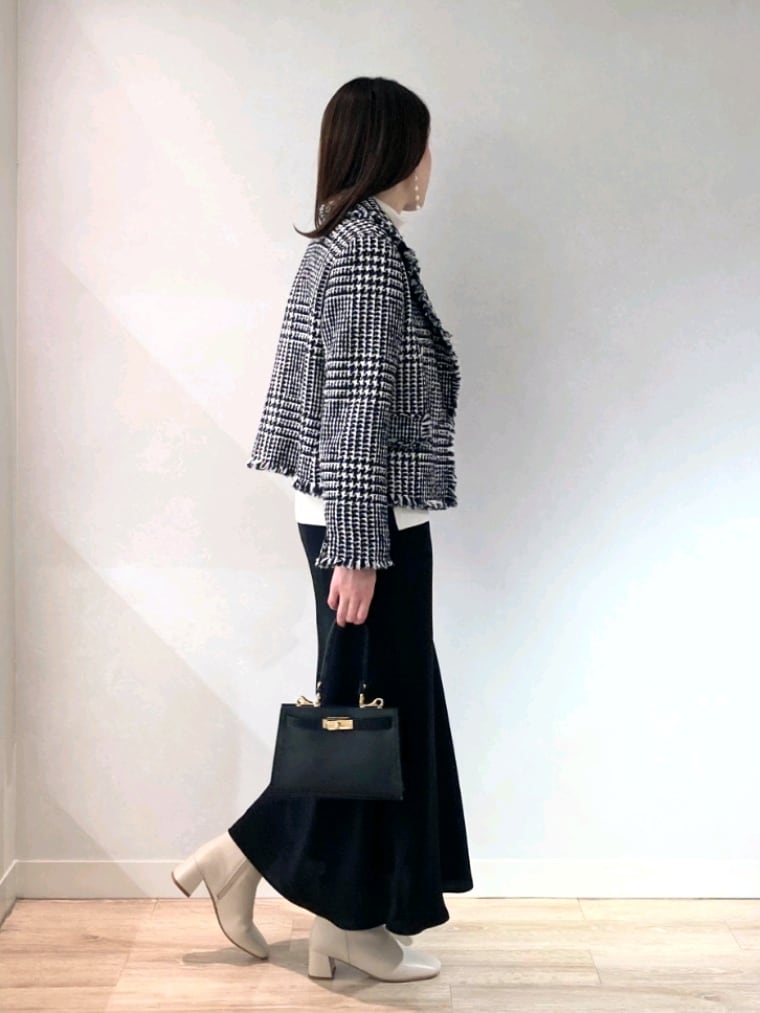 ブラック系のショルダーバッグ、ホワイト系のブーツ、ブラック系のスカートを着用したレディースの冬コーディネートの5枚目の写真