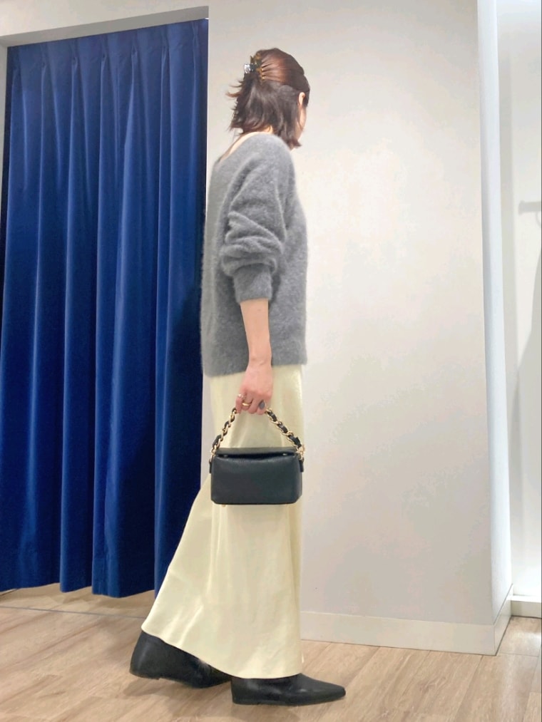 グレー系のニット/セーター、ブラック系のショルダーバッグ、イエロー系のスカートを着用したレディースの秋コーディネートの4枚目の写真