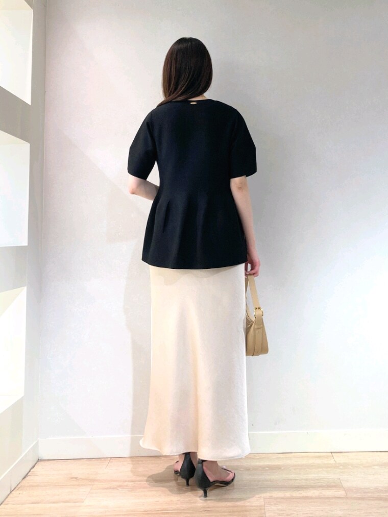 ブラック系のニット/セーター、ベージュ系のショルダーバッグ、ベージュ系のスカートを着用したレディースの春コーディネートの6枚目の写真