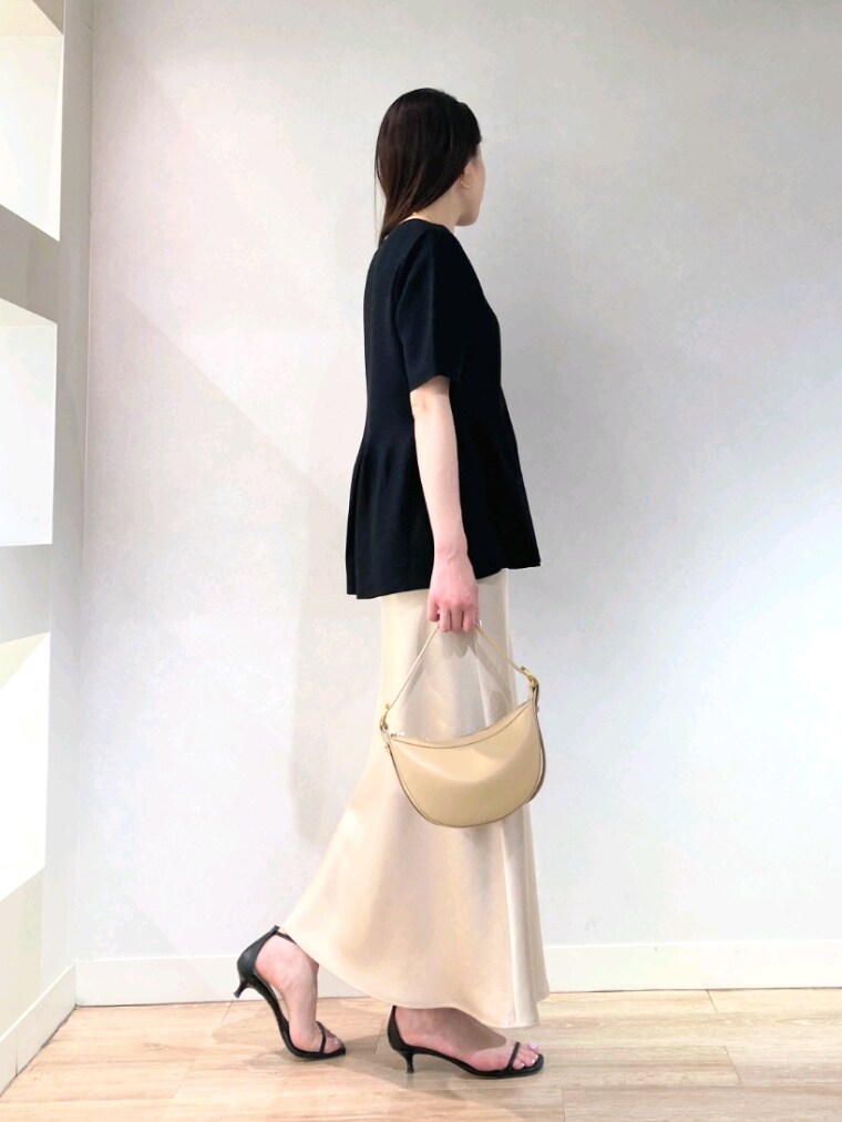 ブラック系のニット/セーター、ベージュ系のショルダーバッグ、ベージュ系のスカートを着用したレディースの春コーディネートの4枚目の写真