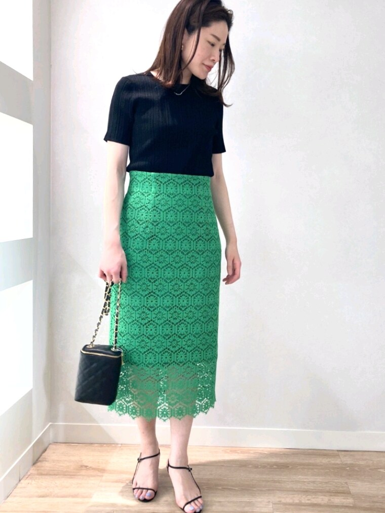 ブラック系のニット/セーター、グリーン系のスカート、ブラック系のサンダルを着用したレディースの春コーディネートの2枚目の写真