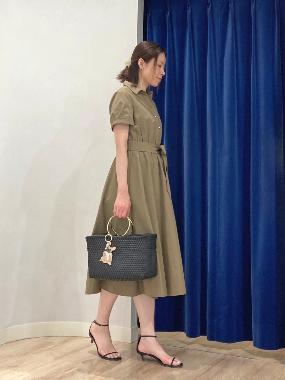 グリーン系のシャツワンピース、ブラック系のかごバッグ、ゴールド系のピアス（両耳用）を着用したレディースの夏コーディネートの4枚目の写真