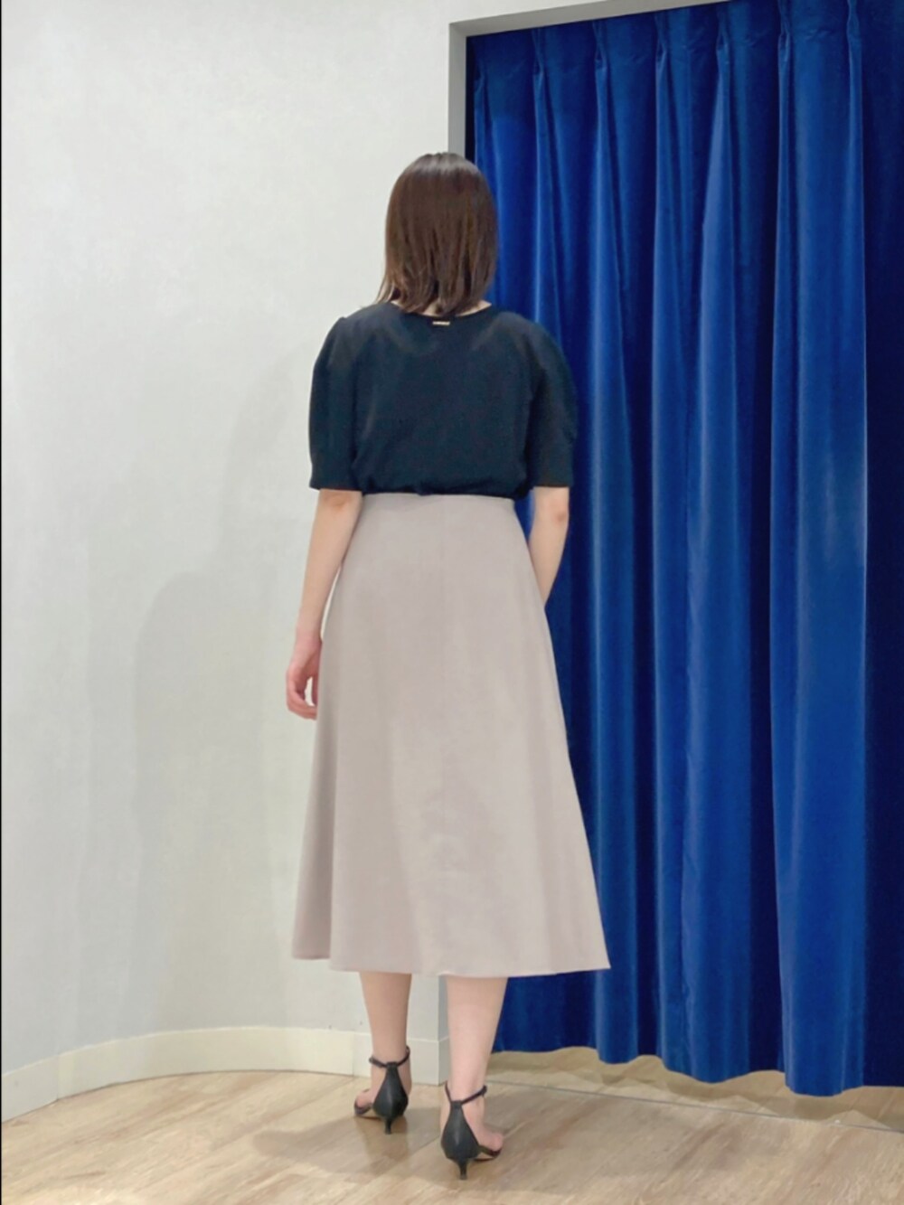 ベージュ系のスカート、ブラック系のTシャツ/カットソー、ゴールド系のピアス（両耳用）を着用したレディースの夏コーディネートの7枚目の写真