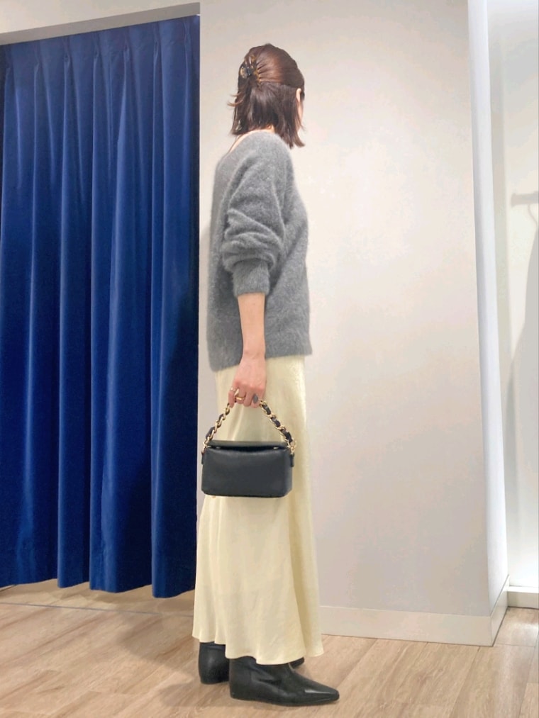 グレー系のニット/セーター、ブラック系のショルダーバッグ、イエロー系のスカートを着用したレディースの秋コーディネートの3枚目の写真