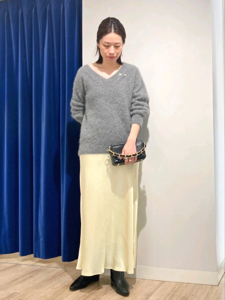 グレー系のニット/セーター、ブラック系のショルダーバッグ、イエロー系のスカートを着用したレディースの秋コーディネートの2枚目の写真