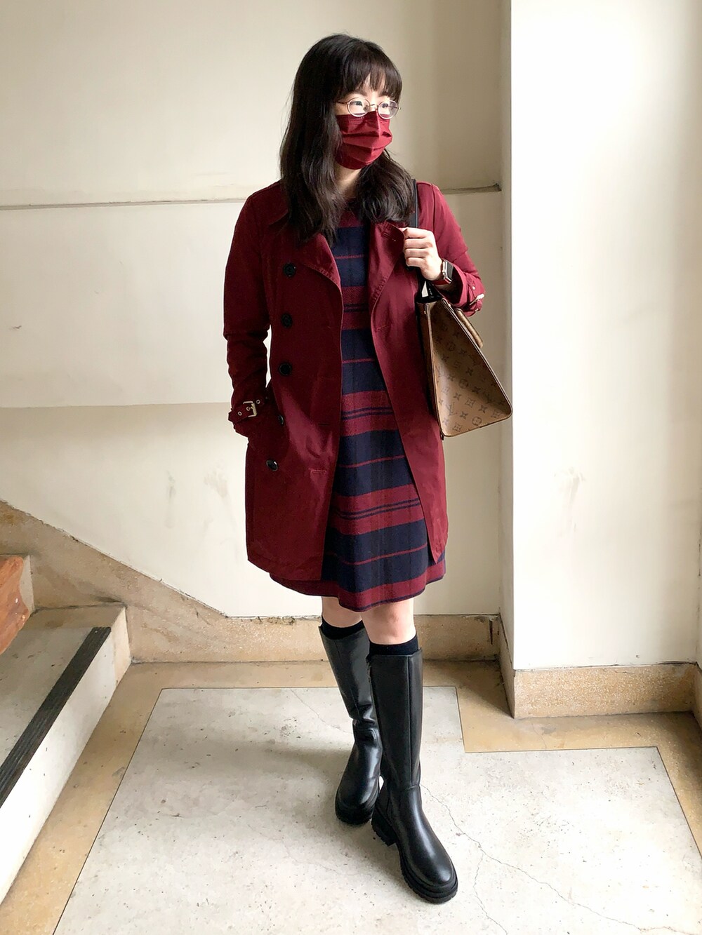 ブラウン系のショルダーバッグ、ブラック系のブーツ、レッド系のトレンチコートを着用したレディースの秋コーディネートの3枚目の写真