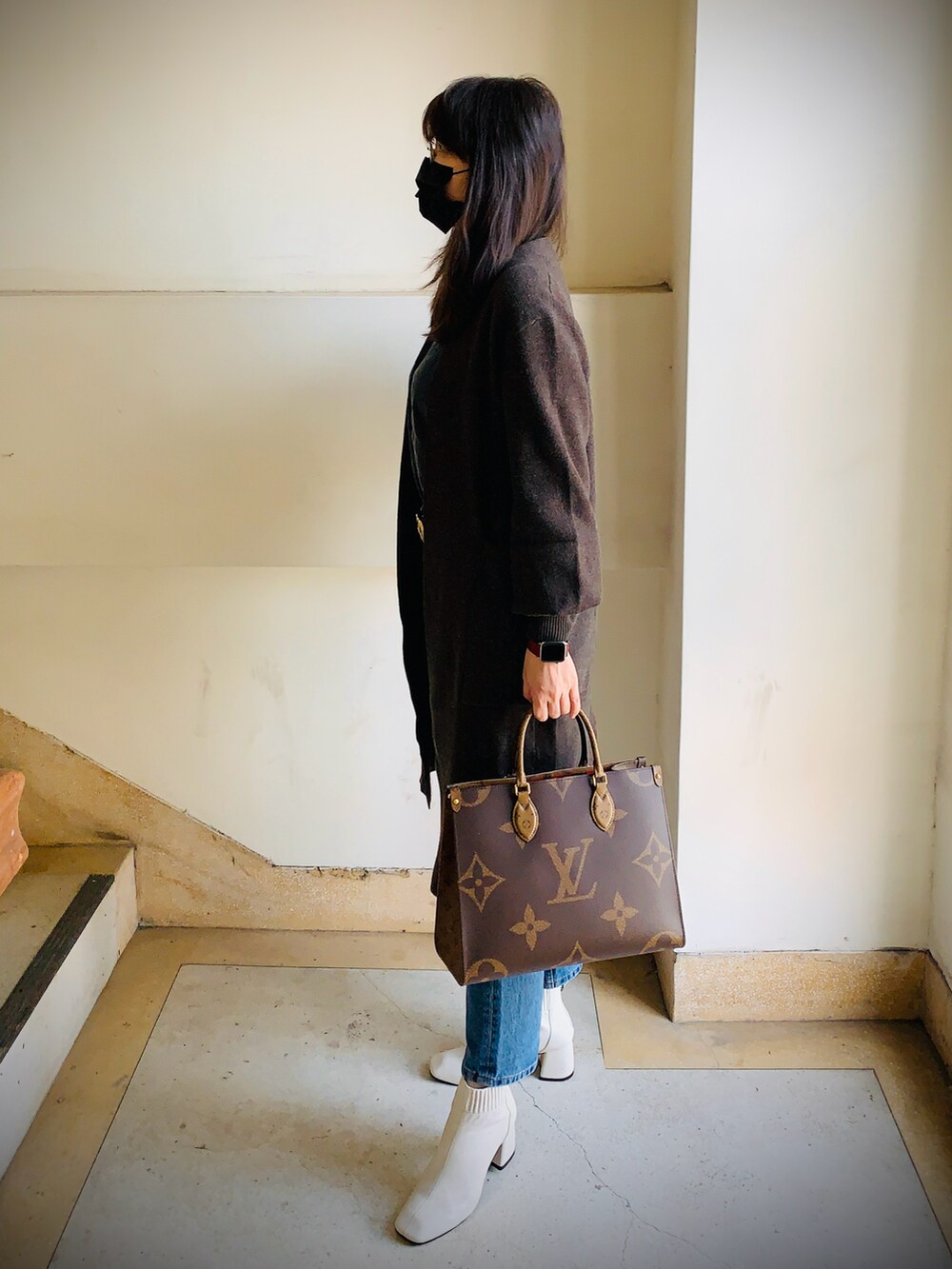 グレー系のピーコート、ブルー系のデニムパンツ、ブラウン系のショルダーバッグを着用したレディースの冬コーディネートの2枚目の写真