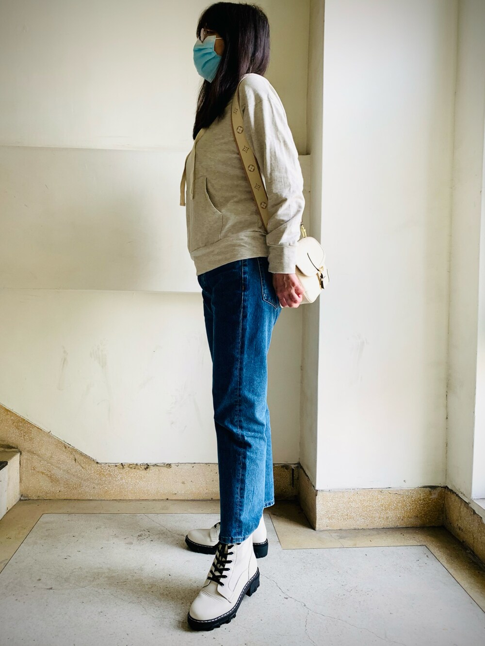ブルー系のデニムパンツ、ホワイト系のブーツ、ベージュ系のショルダーバッグを着用したレディースの冬コーディネートの3枚目の写真