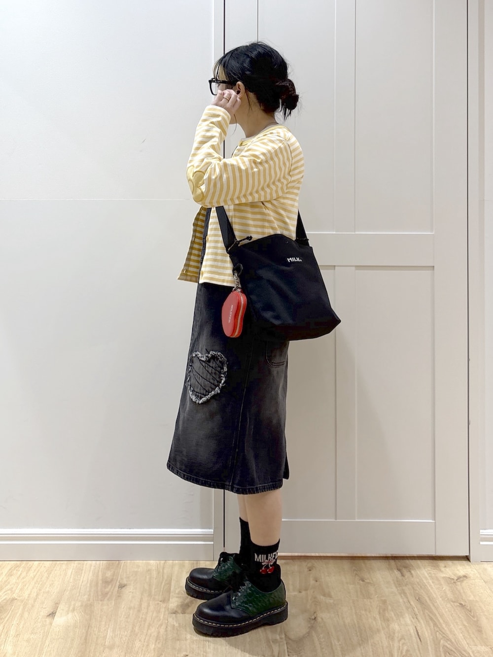 ブラック系のサロペット/オーバーオール、イエロー系のカーディガン/ボレロ、ホワイト系のTシャツ/カットソーを着用したレディースの春コーディネートの2枚目の写真