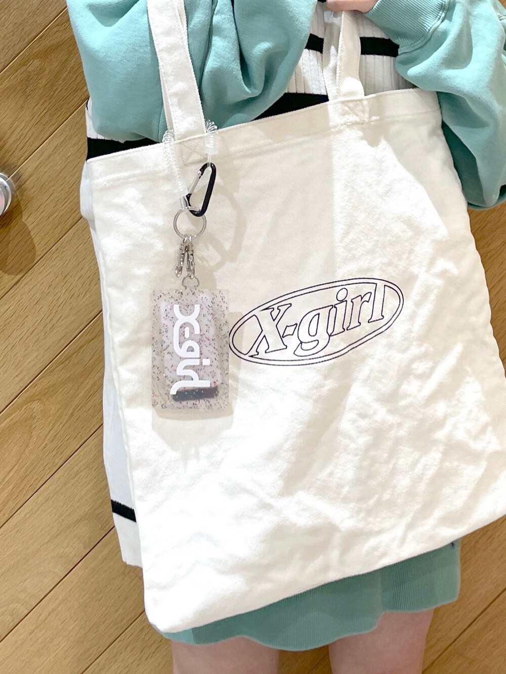 ホワイト系のベスト、グリーン系のワンピース、ホワイト系のトートバッグを着用したレディースの冬コーディネートの2枚目の写真