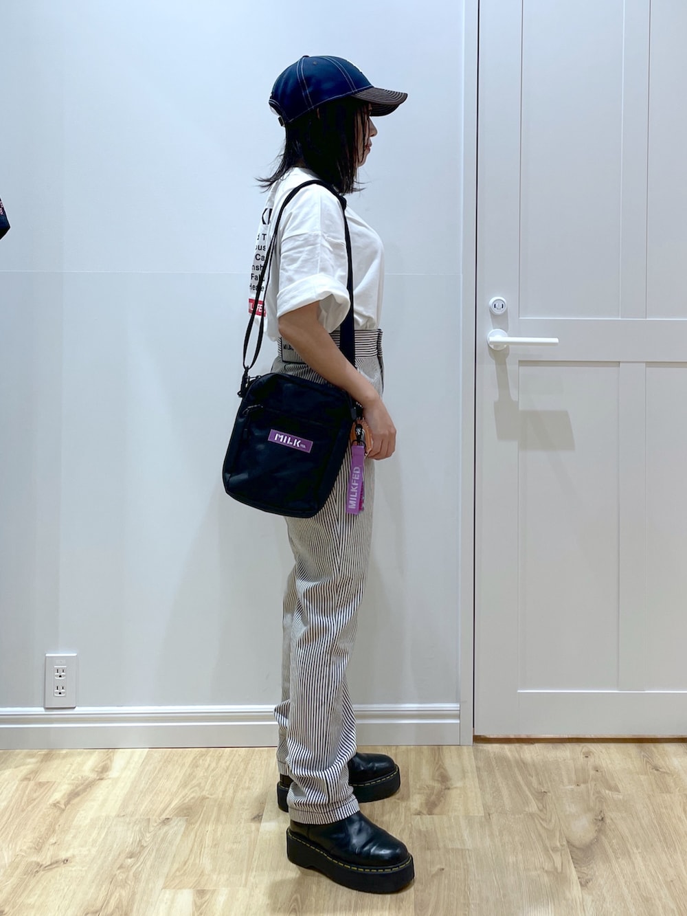 パープル系のショルダーバッグ、ブラック系のブーツ、ブラック系のその他パンツを着用したレディースの夏コーディネートの3枚目の写真