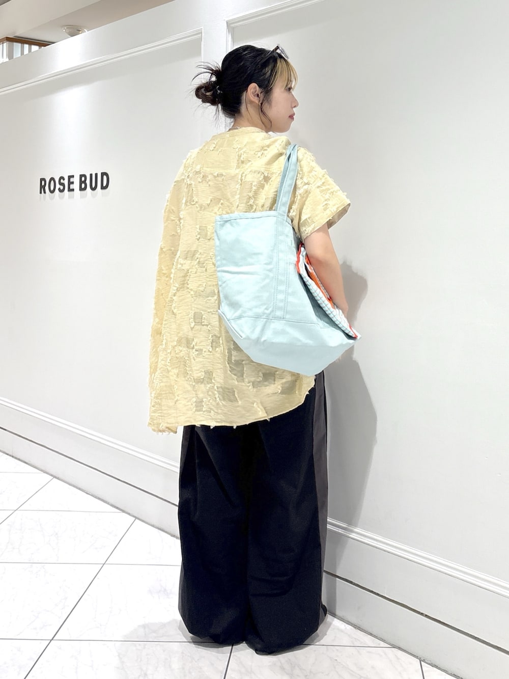 ブルー系のトートバッグ、ベージュ系のシャツ/ブラウス、ホワイト系のベストを着用したレディースの春コーディネートの3枚目の写真