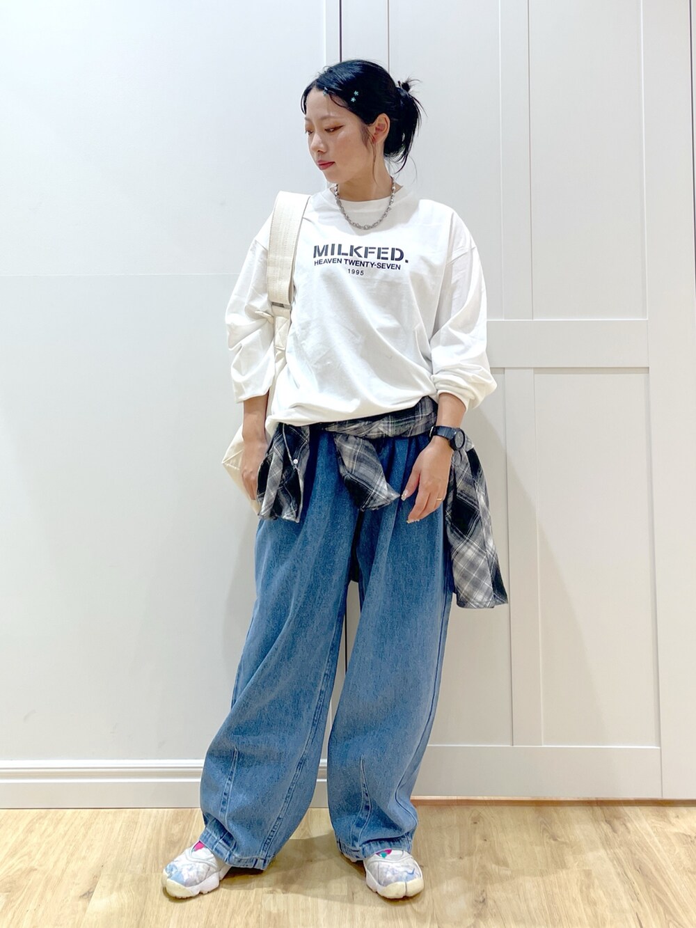 ホワイト系のTシャツ/カットソー、ブラック系のシャツ/ブラウス、ブルー系のデニムパンツを着用したレディースの秋コーディネートの4枚目の写真