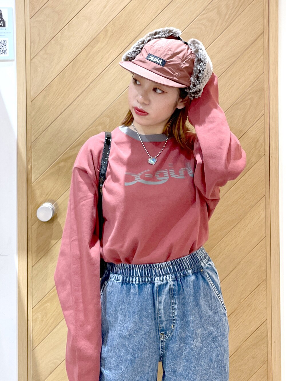ブルー系のデニムパンツ、レッド系のスニーカー、ブラック系のハンドバッグを着用したレディースの秋コーディネートの3枚目の写真