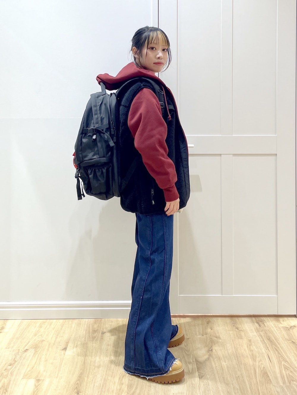 ベージュ系のブーツ、ブルー系のデニムパンツ、ブラック系のベストを着用したレディースの秋コーディネートの3枚目の写真